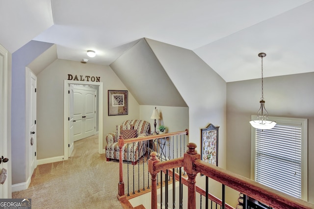 corridor featuring baseboards, light colored carpet, lofted ceiling, and an upstairs landing