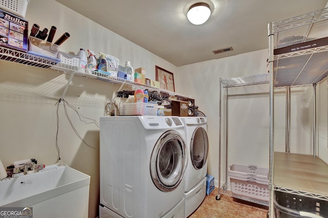 laundry area with laundry area, a sink, washing machine and dryer, and visible vents