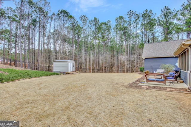 view of yard featuring a storage unit, a patio area, fence, and an outbuilding