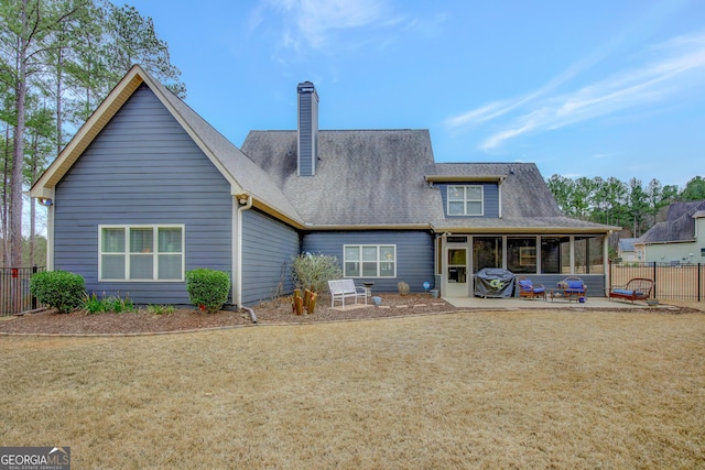 rear view of property featuring fence, a shingled roof, a chimney, a patio area, and a lawn