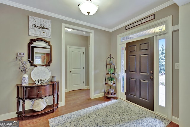 foyer with baseboards, ornamental molding, and wood finished floors