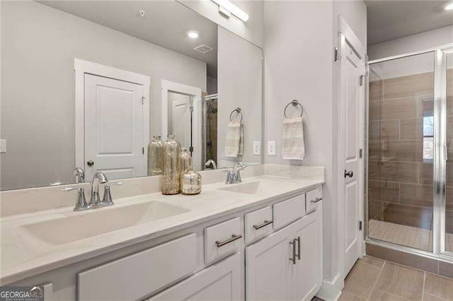 full bathroom with double vanity, a sink, and a shower stall