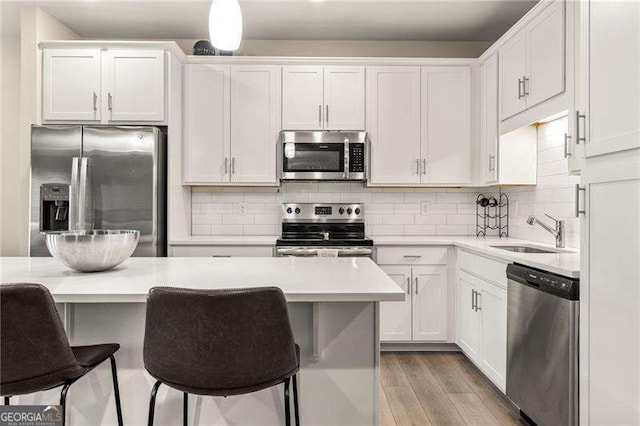 kitchen featuring a breakfast bar area, stainless steel appliances, a sink, and light countertops