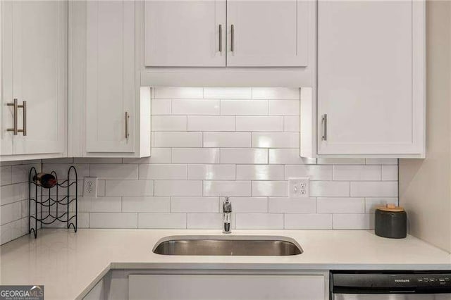 kitchen featuring decorative backsplash, dishwasher, a sink, light countertops, and white cabinets