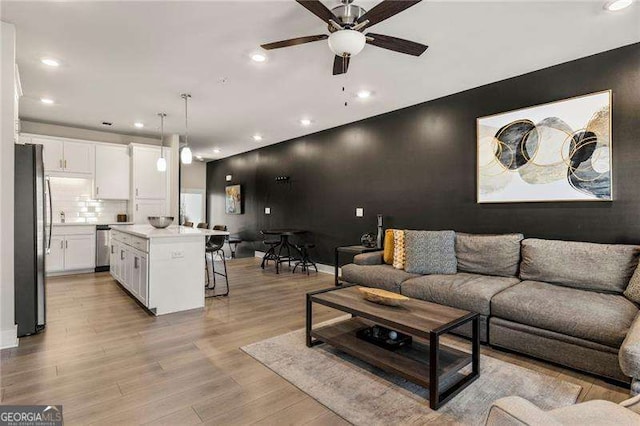 living room with recessed lighting, light wood-style flooring, ceiling fan, and baseboards