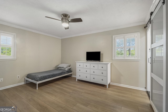 3813 Wingate Dr, Columbus, GA 31909 - bedroom featuring crown molding, ceiling fan, a barn door, baseboards, and light wood-type flooring