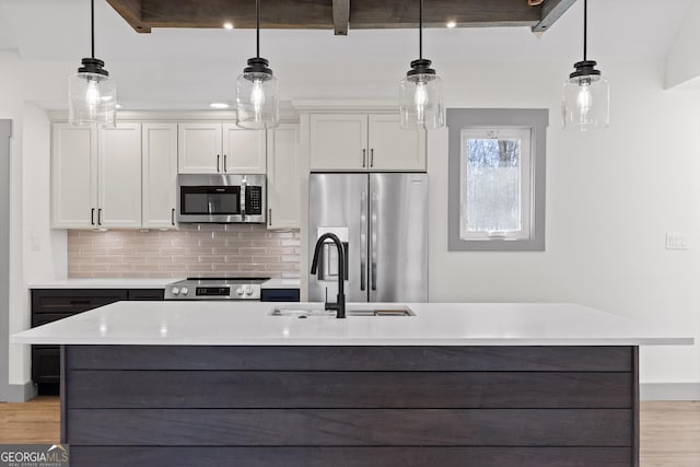 kitchen featuring a sink, light countertops, decorative backsplash, and stainless steel appliances