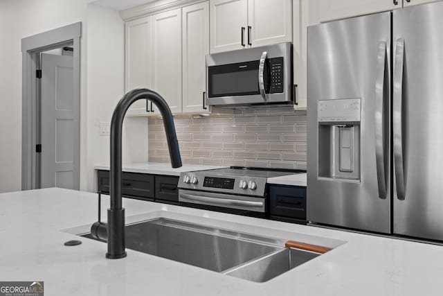 kitchen featuring backsplash, white cabinets, and stainless steel appliances