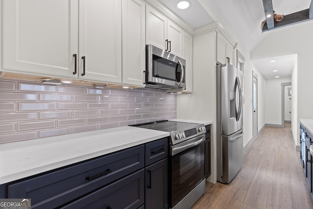 kitchen with light wood-type flooring, light countertops, white cabinetry, tasteful backsplash, and stainless steel appliances