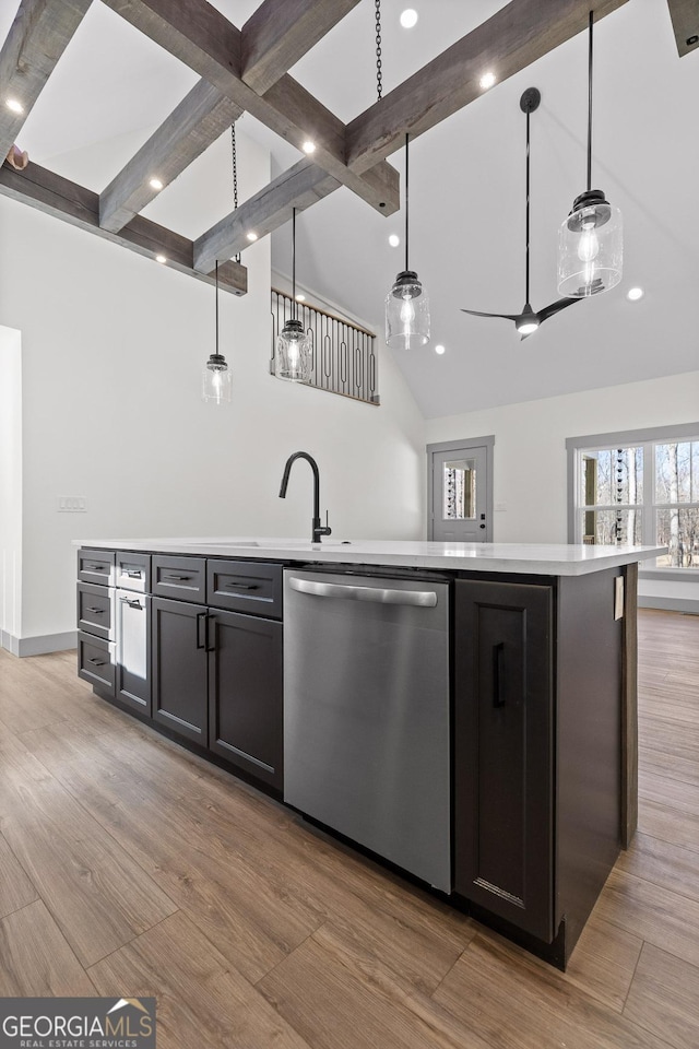 kitchen featuring stainless steel dishwasher, light countertops, light wood finished floors, and beam ceiling
