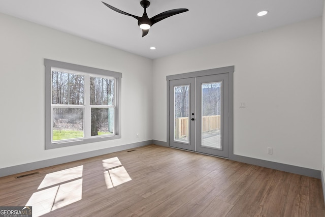 spare room with french doors, visible vents, a healthy amount of sunlight, and wood finished floors