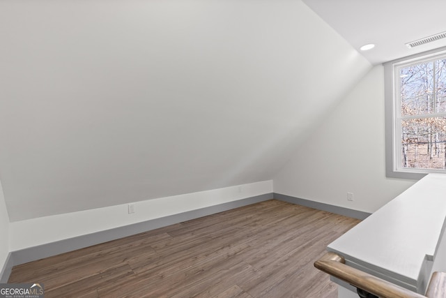 bonus room featuring baseboards, vaulted ceiling, wood finished floors, and visible vents