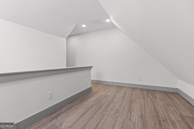 additional living space with recessed lighting, vaulted ceiling, wood finished floors, and visible vents
