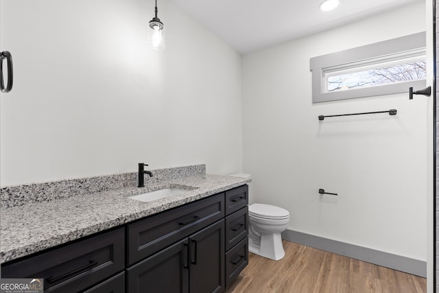 bathroom featuring wood finished floors, vanity, baseboards, toilet, and recessed lighting