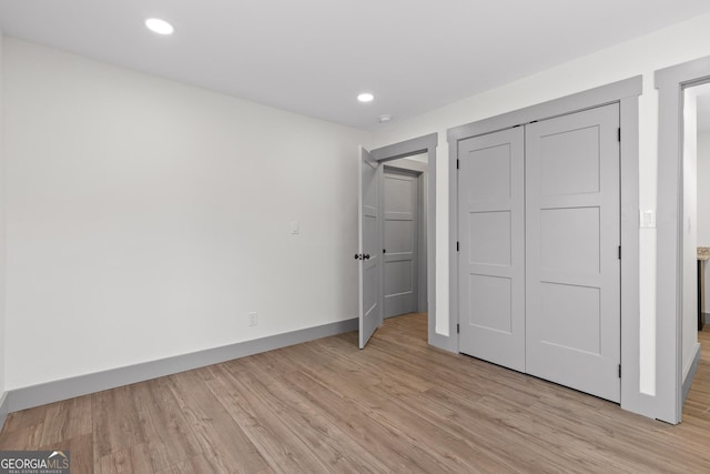 unfurnished bedroom with light wood-style floors, baseboards, a closet, and recessed lighting