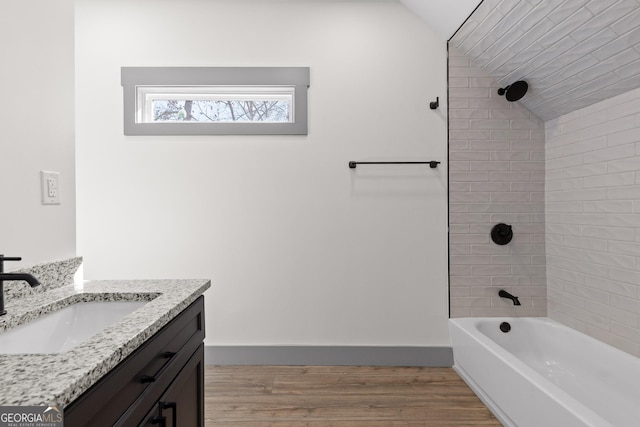 full bathroom with vanity, lofted ceiling, wood finished floors, bathing tub / shower combination, and baseboards