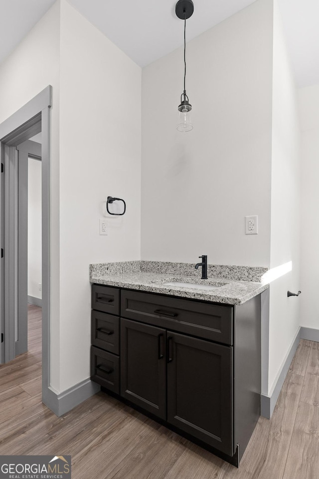 bathroom with baseboards, vanity, and wood finished floors