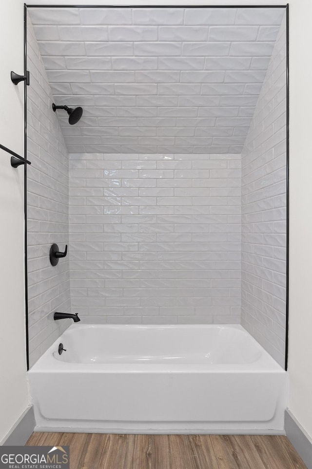 full bathroom featuring baseboards, vaulted ceiling, wood finished floors, and tub / shower combination