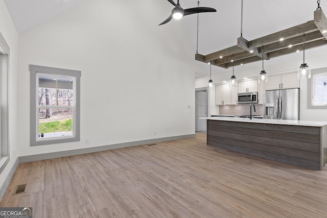 kitchen with visible vents, ceiling fan, high vaulted ceiling, light countertops, and stainless steel appliances
