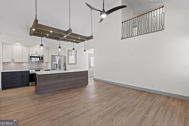 kitchen with white cabinets, light countertops, high vaulted ceiling, stainless steel appliances, and backsplash