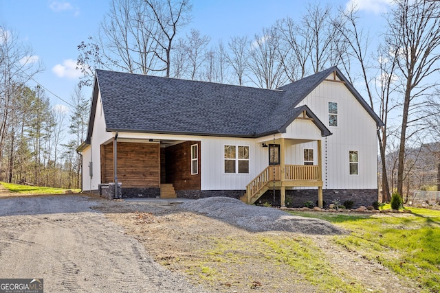 modern farmhouse with a shingled roof and dirt driveway