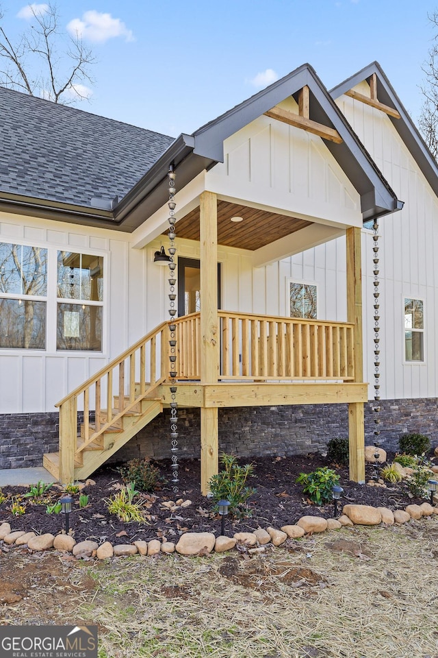 rear view of house featuring board and batten siding, covered porch, and roof with shingles