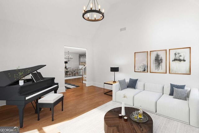 living area featuring high vaulted ceiling, a chandelier, baseboards, wood finished floors, and visible vents