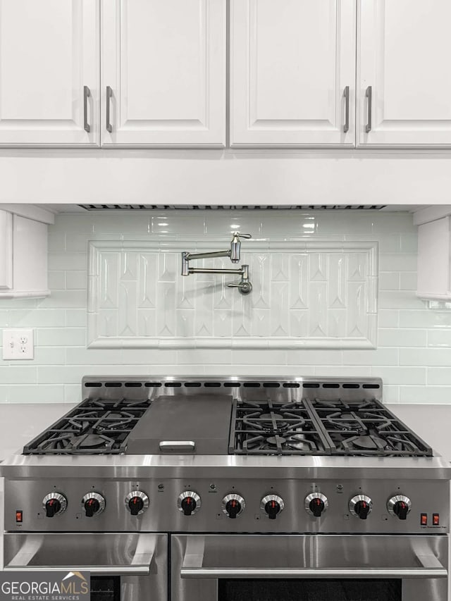 kitchen featuring decorative backsplash, high end stainless steel range oven, and white cabinetry