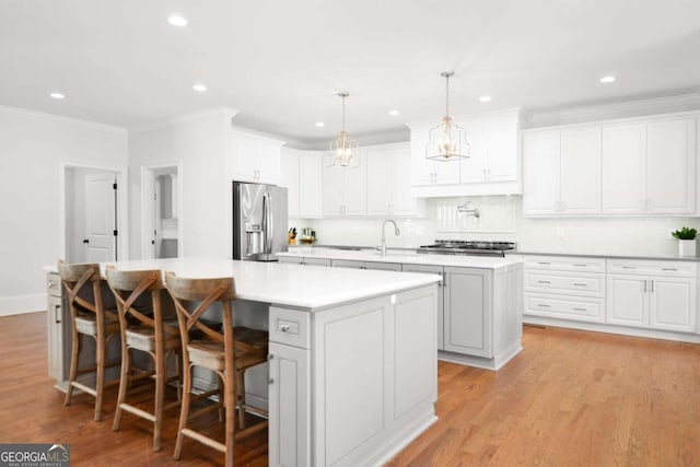kitchen featuring light countertops, light wood finished floors, appliances with stainless steel finishes, and a kitchen island with sink