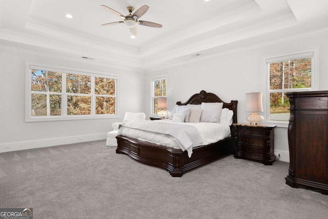carpeted bedroom with crown molding, baseboards, ceiling fan, and a raised ceiling