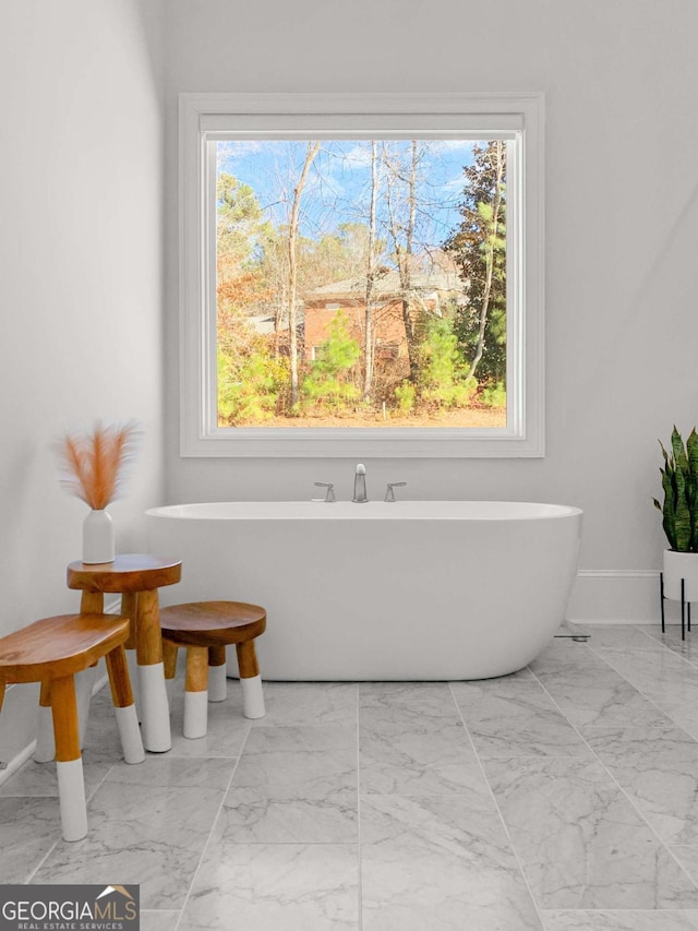 bathroom featuring baseboards, a soaking tub, and marble finish floor