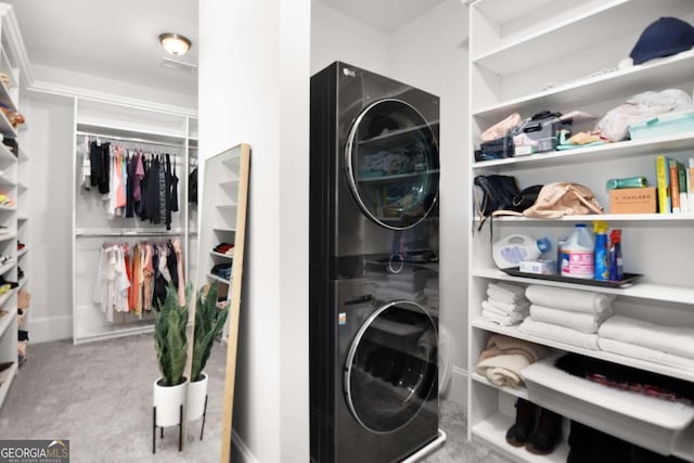 washroom featuring laundry area, stacked washer / dryer, and carpet