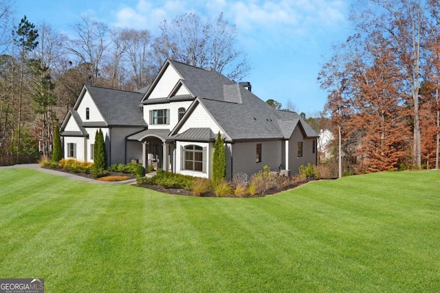 view of front facade with a standing seam roof, roof with shingles, metal roof, and a front yard
