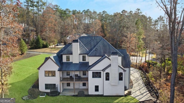 back of property with a yard, a chimney, and a shingled roof