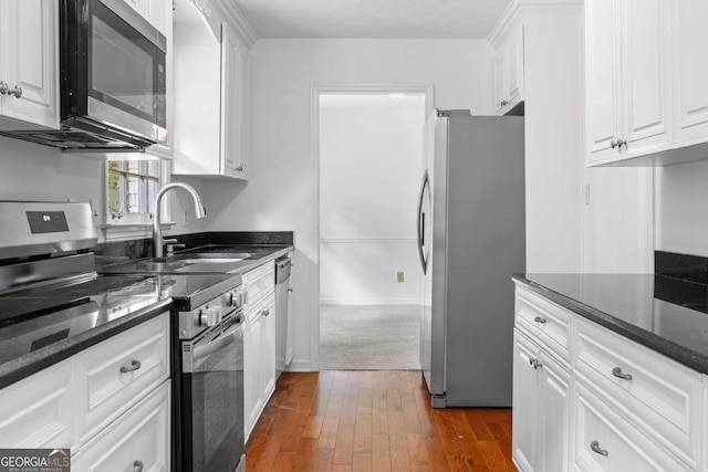 380 Grady Ave, Fayetteville, GA 30214 - kitchen featuring appliances with stainless steel finishes, a sink, dark wood finished floors, dark stone countertops, and white cabinetry