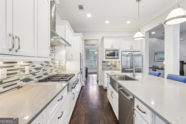 kitchen with wall chimney range hood, visible vents, appliances with stainless steel finishes, white cabinets, and dark wood-type flooring