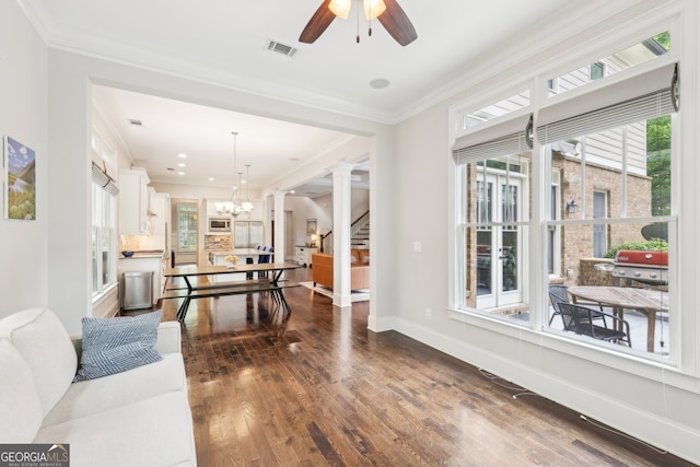 living room with crown molding, dark wood-style flooring, visible vents, and ceiling fan with notable chandelier