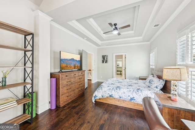 bedroom featuring baseboards, wood finished floors, a tray ceiling, visible vents, and ornamental molding