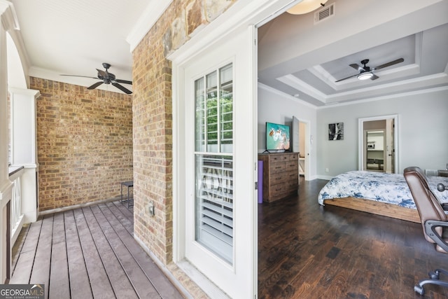 bedroom featuring visible vents, ornamental molding, wood-type flooring, brick wall, and a raised ceiling