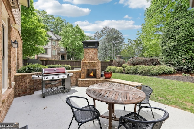 view of patio featuring fence, an outdoor brick fireplace, and area for grilling