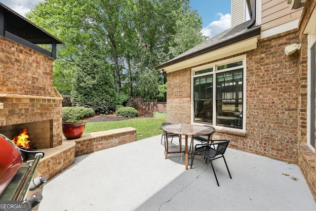 view of patio / terrace with outdoor dining space, fence, and an outdoor brick fireplace