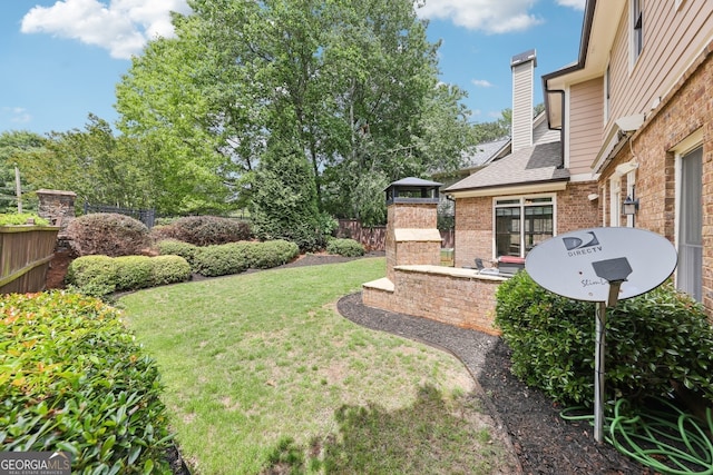 view of yard with fence and a fireplace