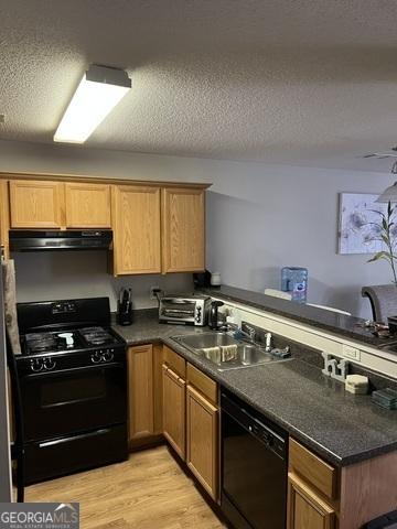 kitchen with a sink, ventilation hood, light wood-style floors, a textured ceiling, and black appliances