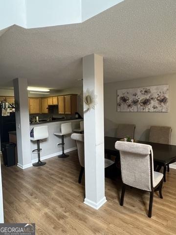 dining space with a textured ceiling, baseboards, and light wood-style floors