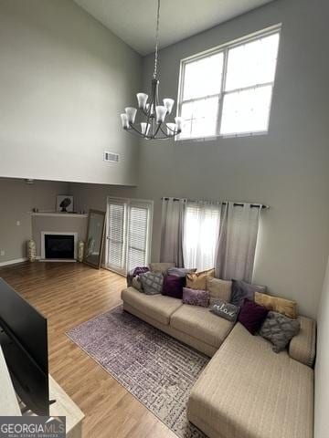 living area with high vaulted ceiling, a notable chandelier, a healthy amount of sunlight, and visible vents