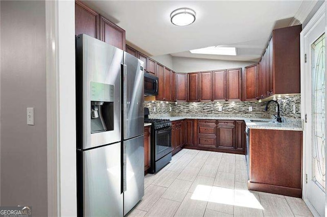 kitchen featuring a sink, tasteful backsplash, black appliances, light wood-style flooring, and light stone countertops
