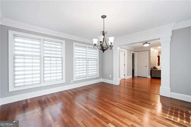 unfurnished dining area with baseboards, a chandelier, wood finished floors, and decorative columns