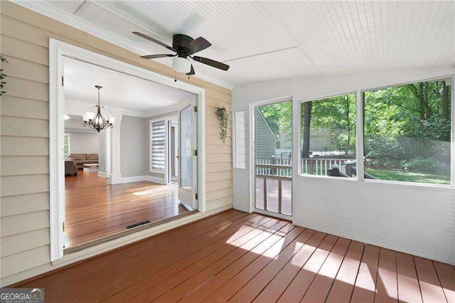 unfurnished sunroom featuring ornamental molding, wood walls, wood-type flooring, and a notable chandelier
