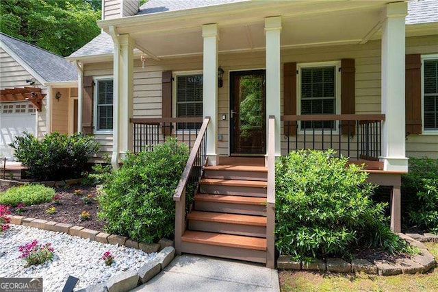 view of exterior entry featuring a chimney, roof with shingles, covered porch, and a garage