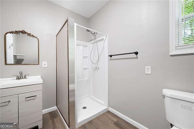 bathroom featuring vanity, baseboards, a shower stall, and wood finished floors